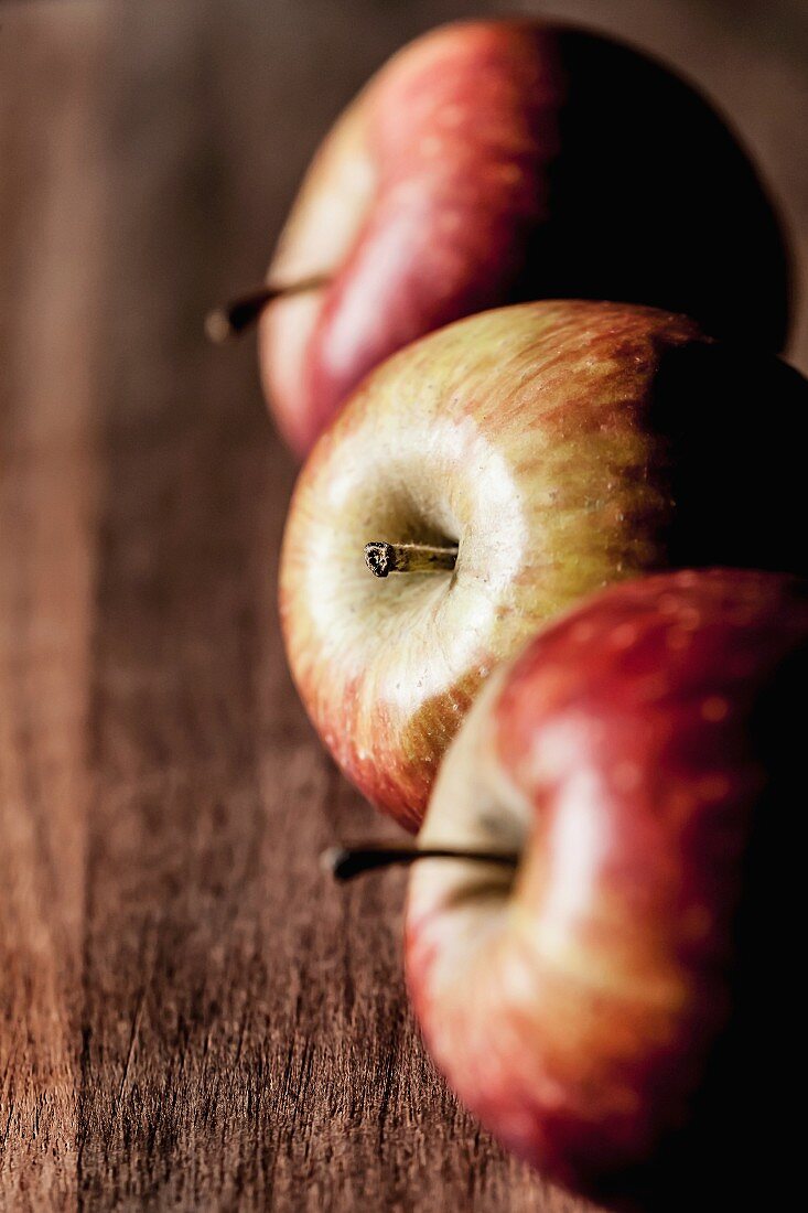 Drei Äpfel in einer Reihe auf Holzuntergrund
