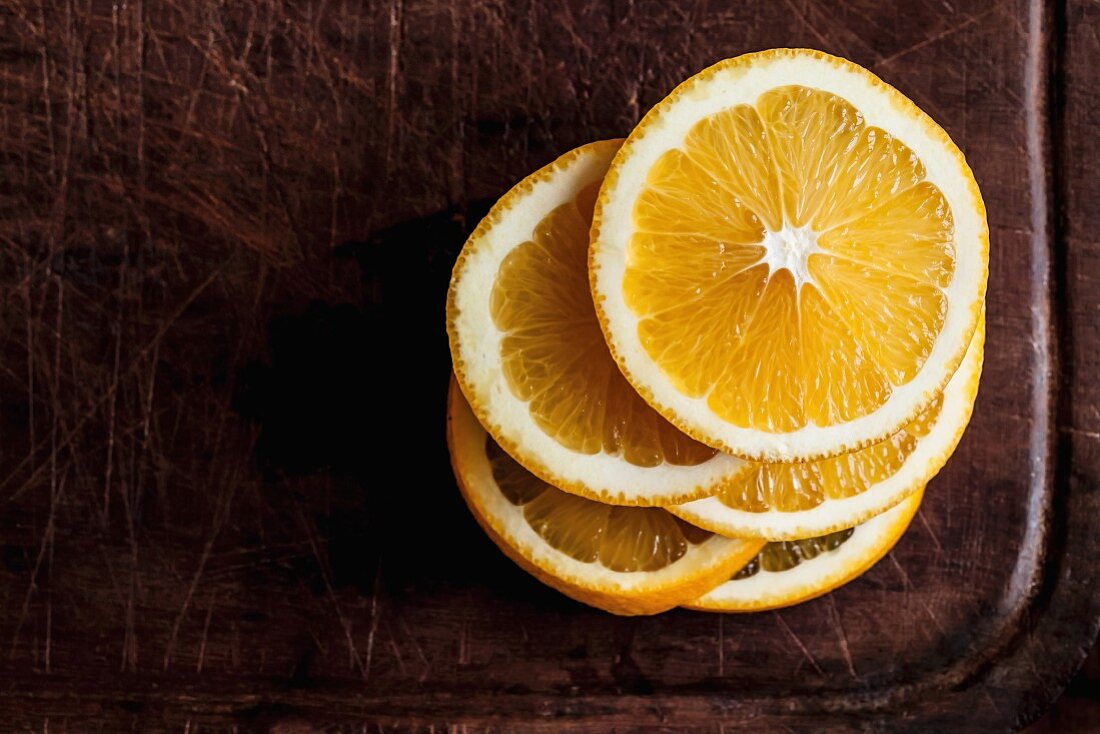 A stack of orange slices on a wooden chopping board