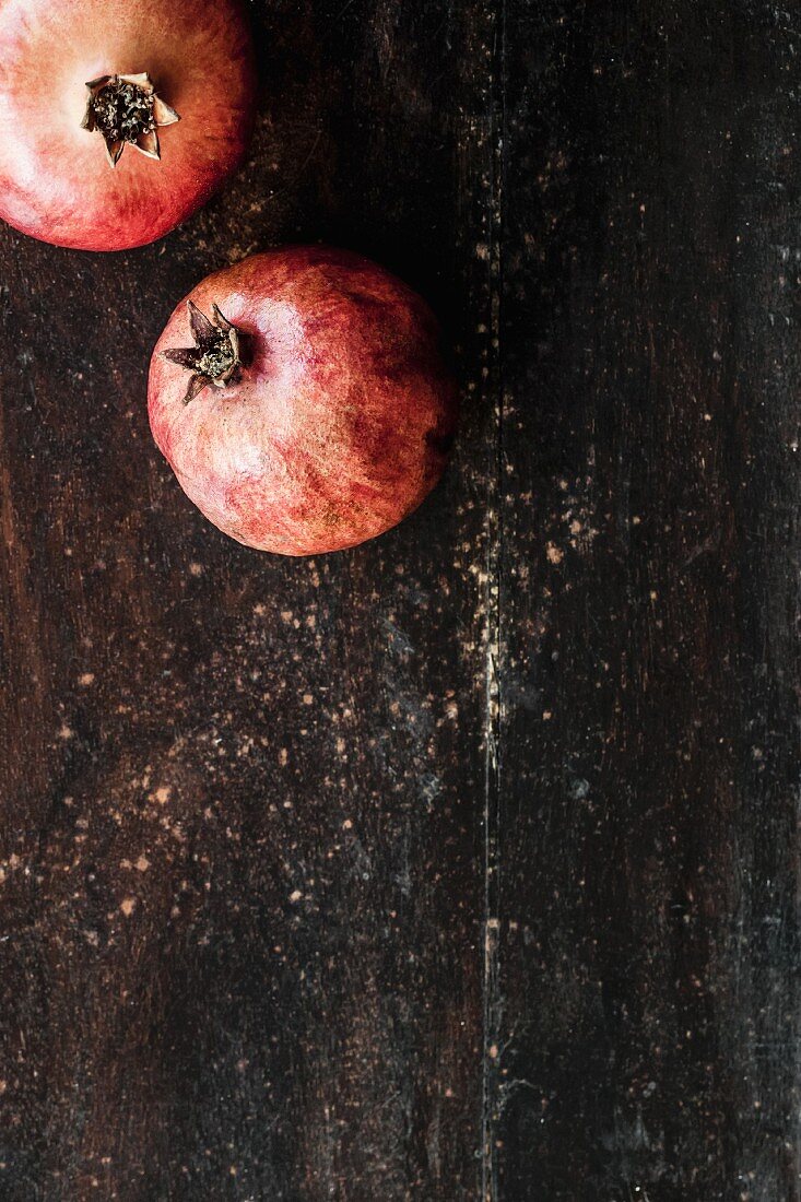 Zwei Granatäpfel auf Holzuntergrund (Draufsicht)
