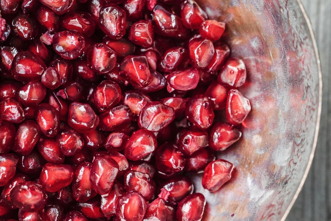 Pomegranate seeds in a metal bowl (close-up)