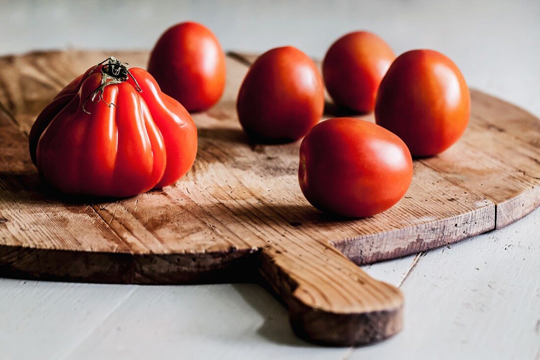 Several tomatoes on a round wooden board