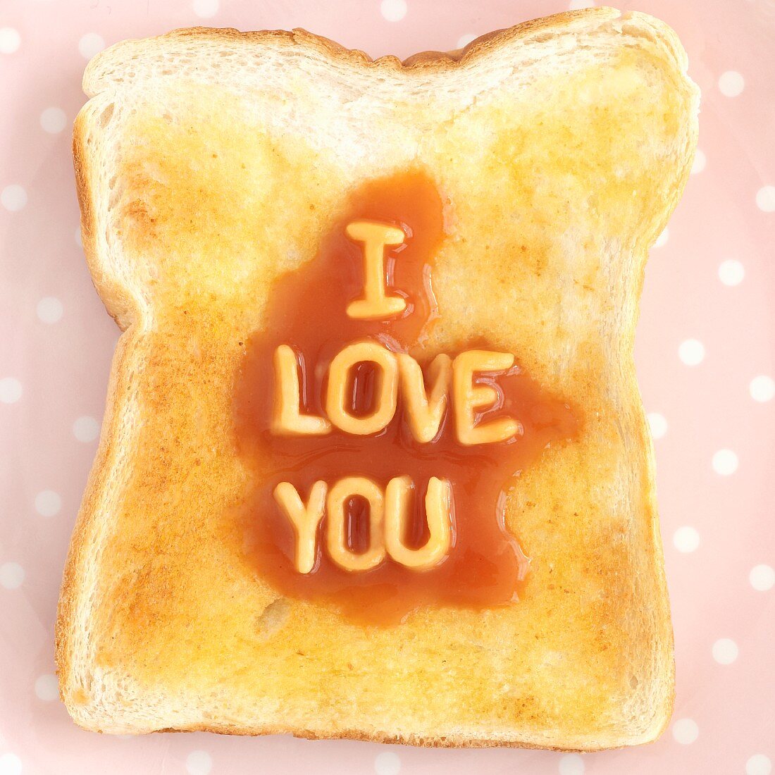 A slice of toast with spaghetti letters spelling out I LOVE YOU