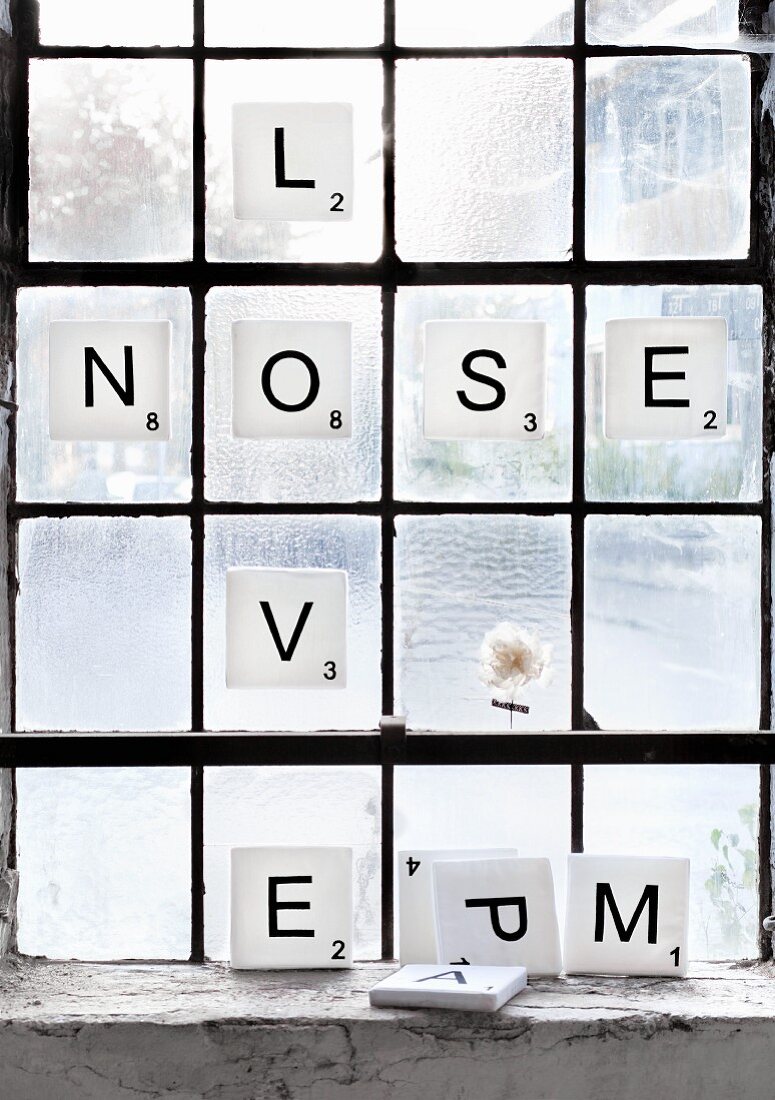 Scrabble-Steine: weiss bezogene Schaumstoffplatten mit schwarzen Buchstaben als Fensterdeko