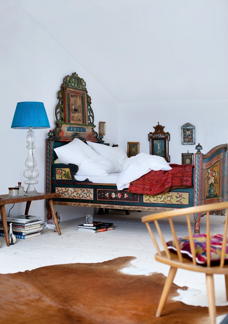 Bemaltes Bauernbett aus dem 19. Jahrhundert, flankiert von alten Bildern mit religiösen Motiven und italienischer Leuchte mit Glasfuss