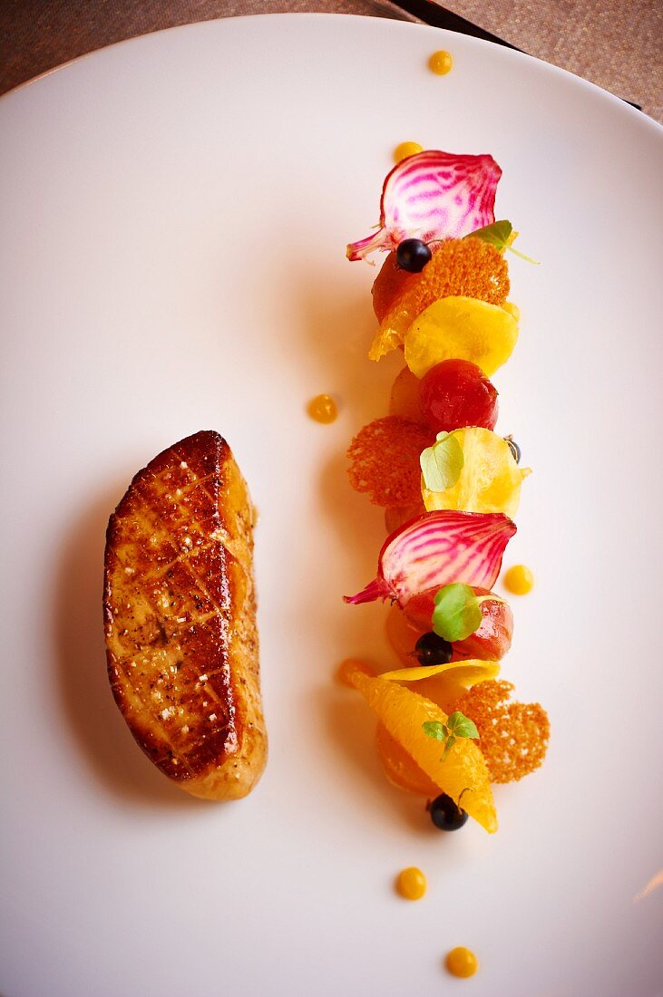 Fried goose liver with a side of fruit and vegetables