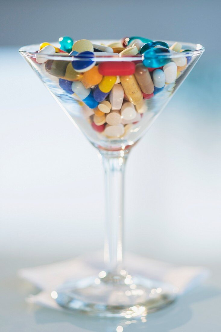 Lots of different tablets and pills in a cocktail glass