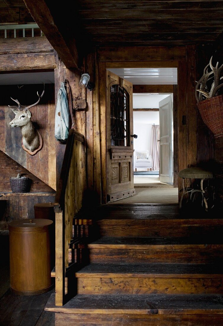 Ehemalige Scheune dient als Diele - Tiertrophäe an Holzwand, daneben Holztreppe vor offener Tür
