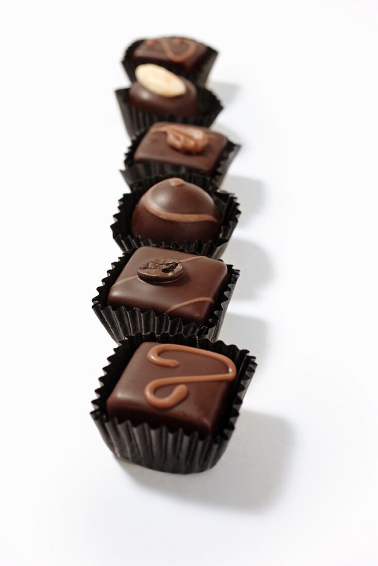 A row of assorted filled chocolates in paper cases