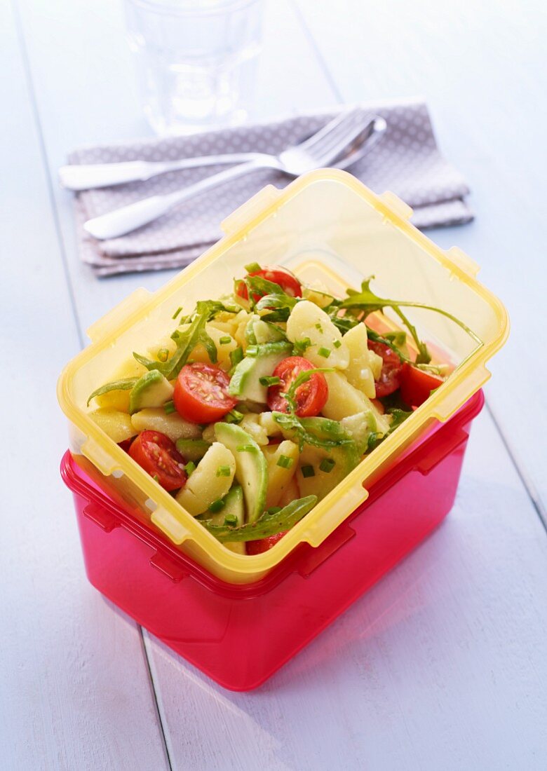 Potato salad with avocado and cherry tomatoes in a Tupperware container