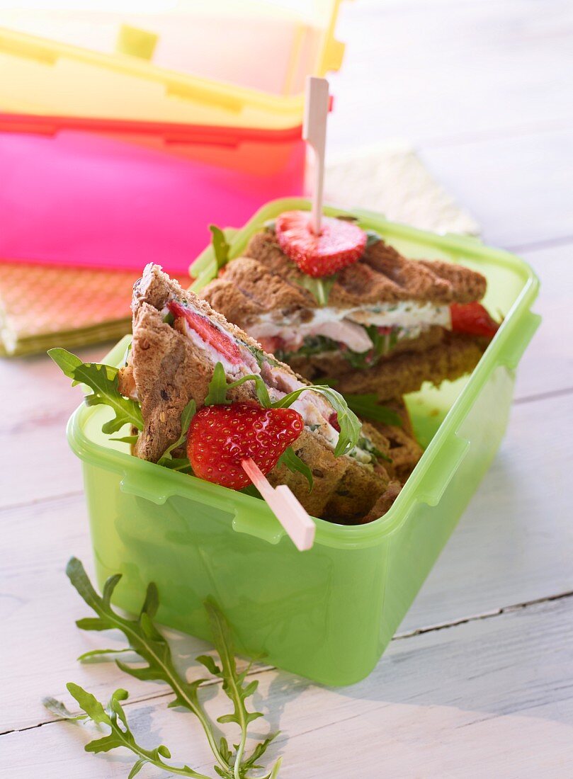 Strawberry and chicken sandwiches in a Tupperware container