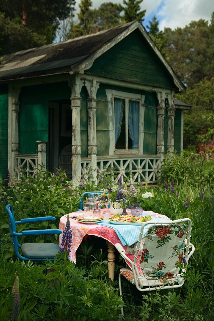 A table laid in a garden in front of a wooden house in Sweden