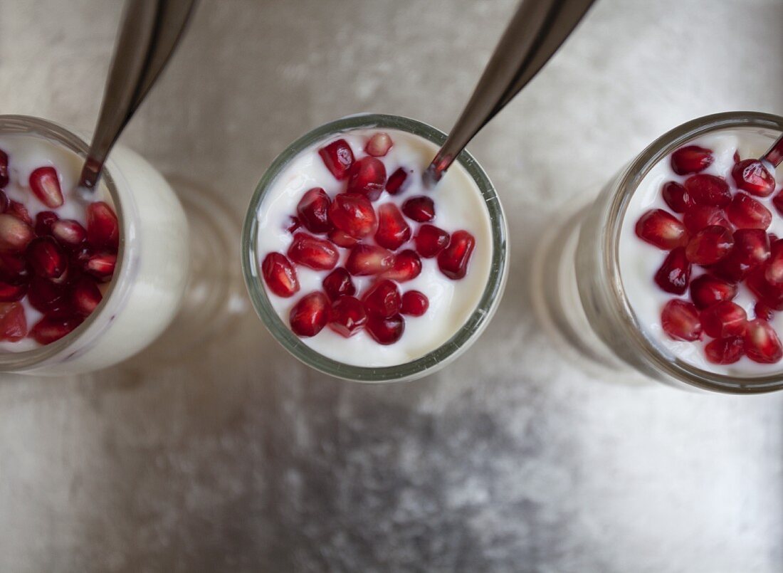 Yoghurt with pomegranate seeds in three glasses