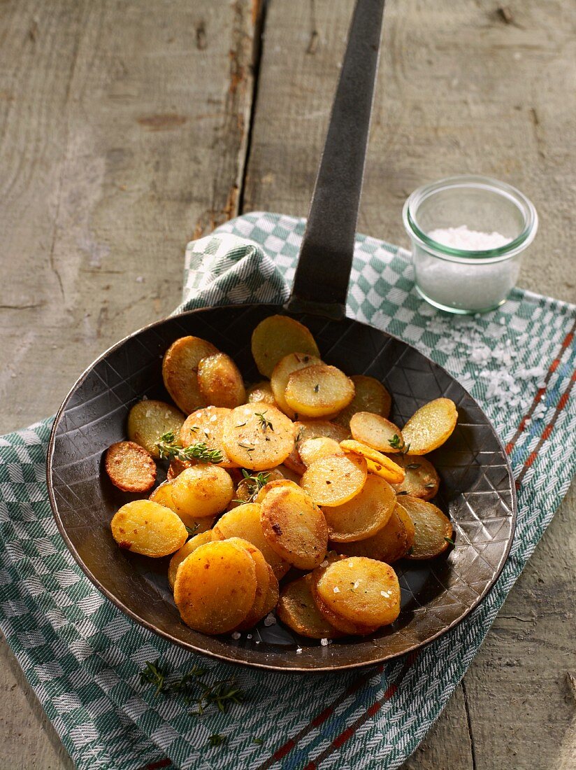 Fried potatoes in a pan on a tea towel