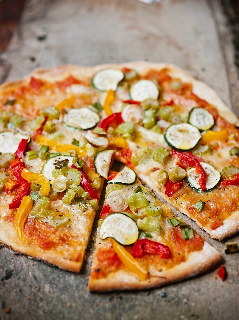 Vegetable pizza with courgette and peppers, one slice cut