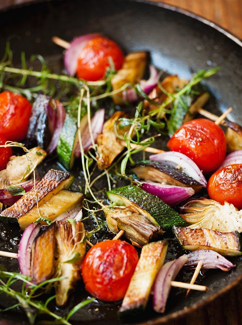 Gemüsespiesse mit Kirschtomaten, Zucchini und Zwiebeln in Pfanne