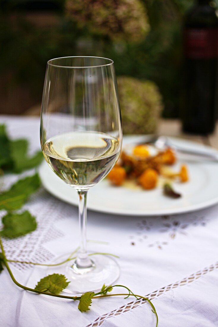 Ein Glas Weißwein auf einem herbstlichem Tisch