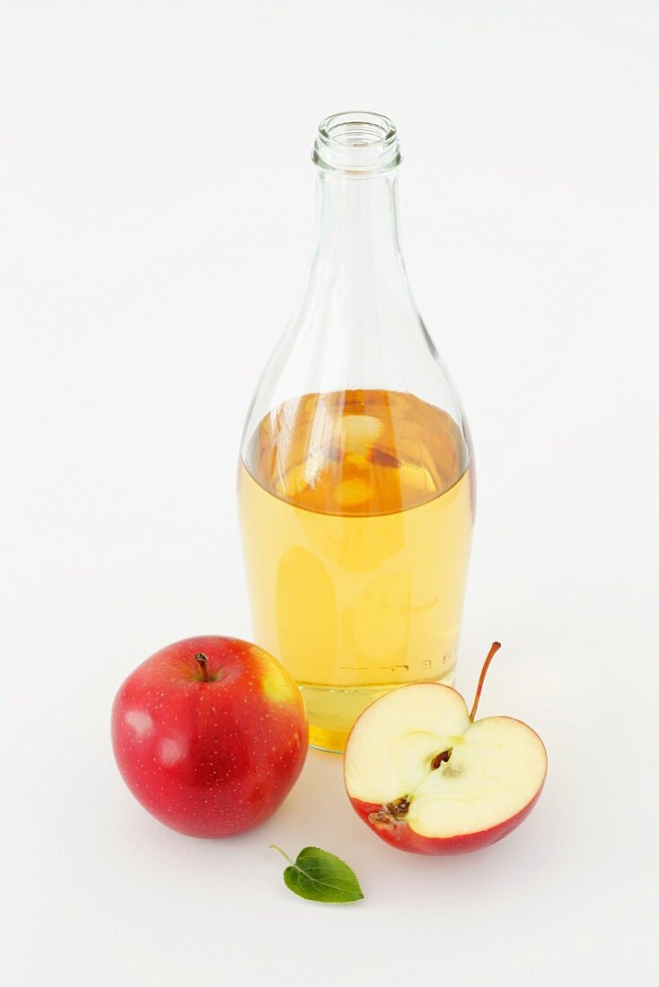 Eine Flasche Apfelessig und frische Äpfel