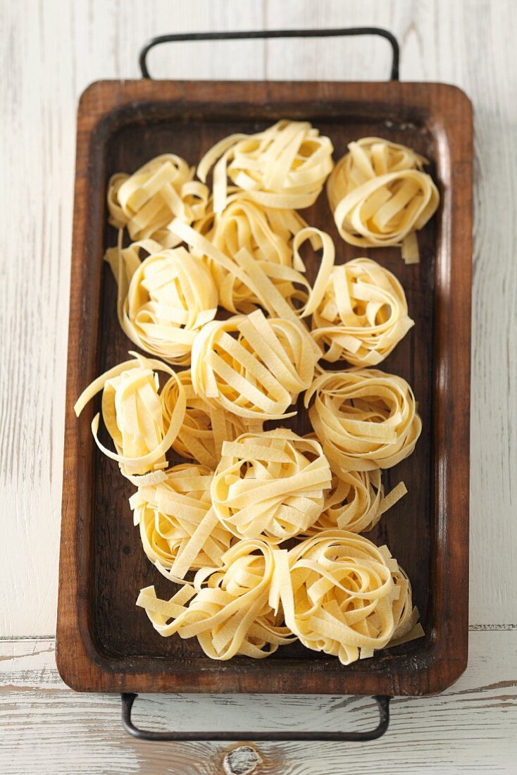 Lots of tagliatelle nests on a wooden tray