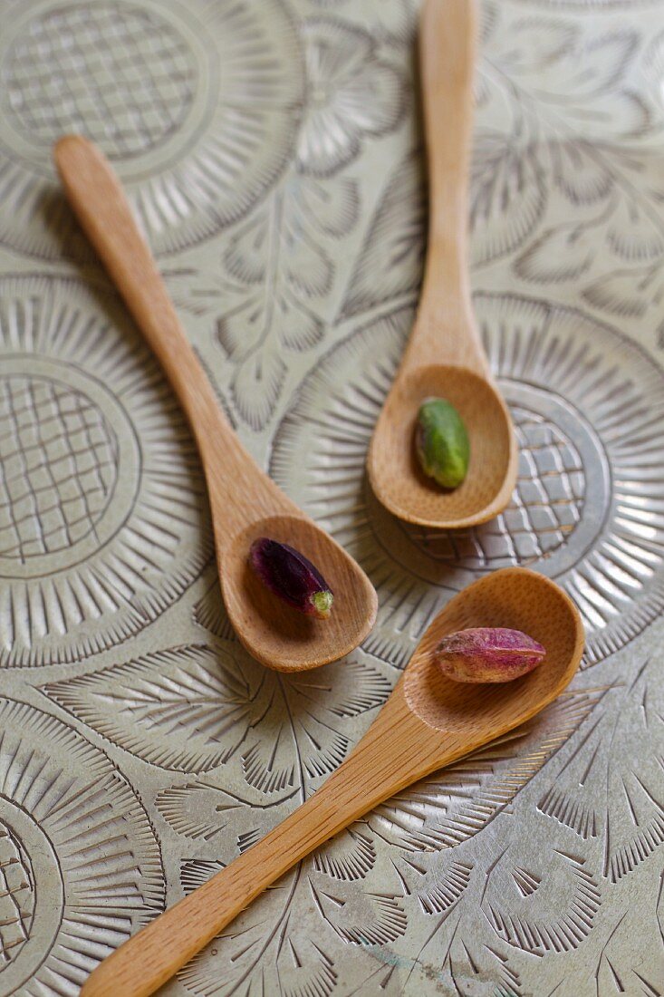 Three wooden spoons with pistachios