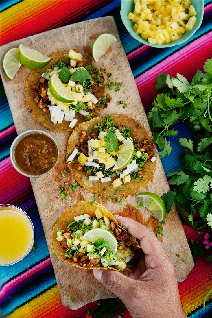 Hand hält Taco al pastor (Maistortillas mit Schweinefleisch, Mexico)