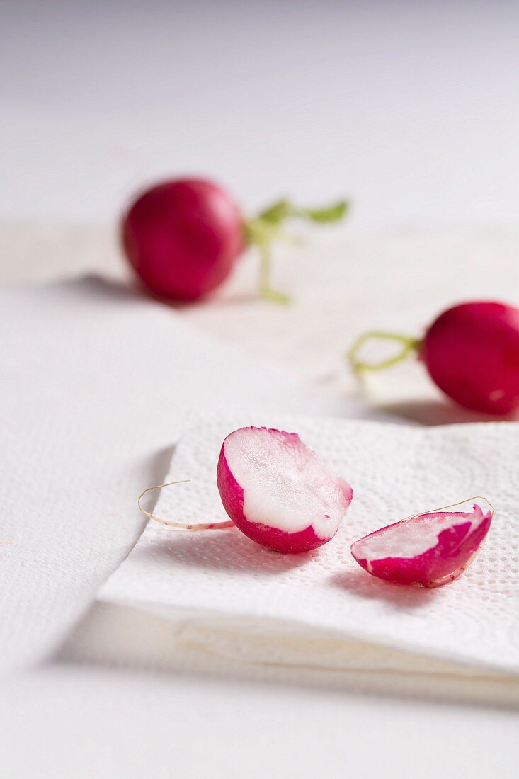 Radishes, whole and sliced in two, on kitchen paper