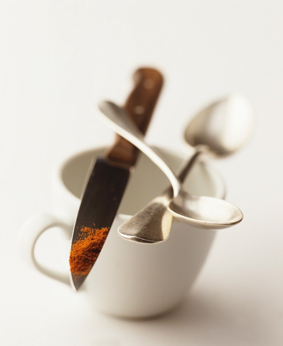Stillleben mit Tasse, Kaffeelöffeln & Gewürzpulver auf Messerspitze