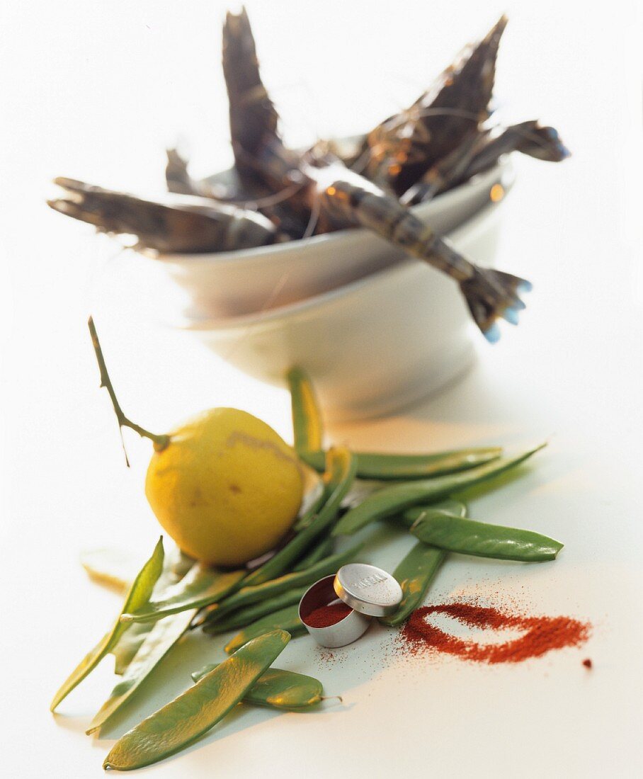 A still life of ingredients featuring prawns, mange tout, a lemon and saffron