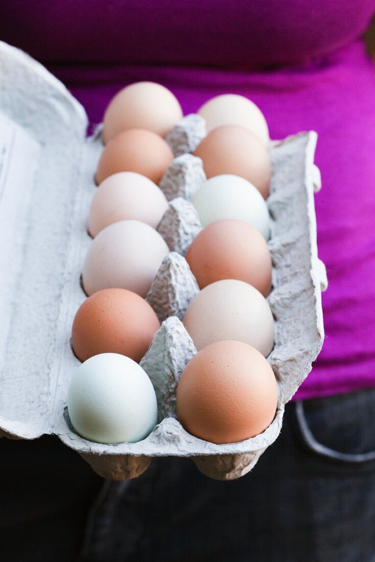 Frau hält Eierkarton mit frischen Bioeiern