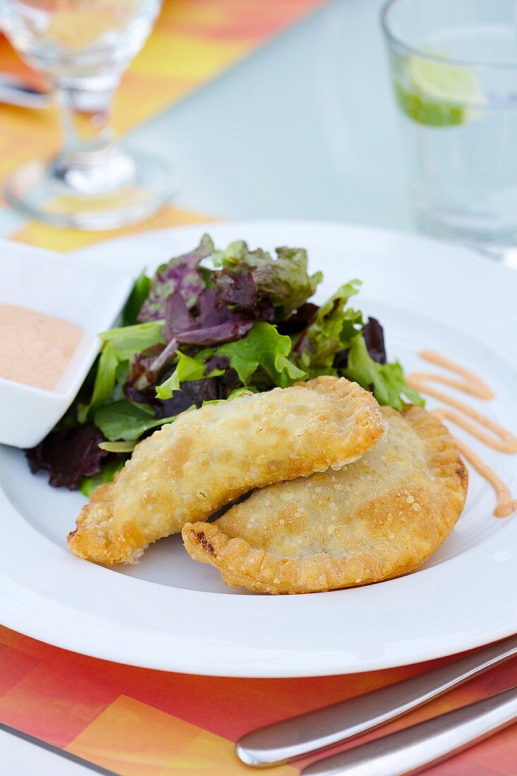 Empanadas on a plate with a green salad