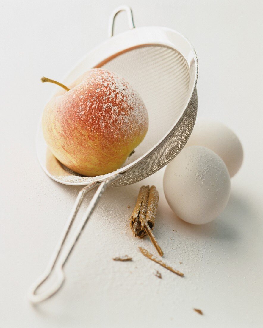 An apple, eggs, cinnamon and icing sugar