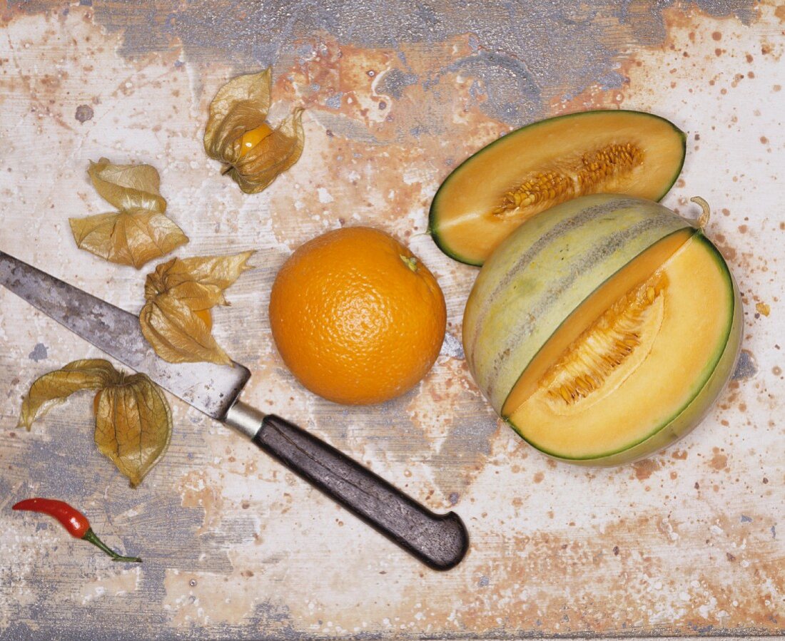 Angeschnittene Melone, Orange und Physalis
