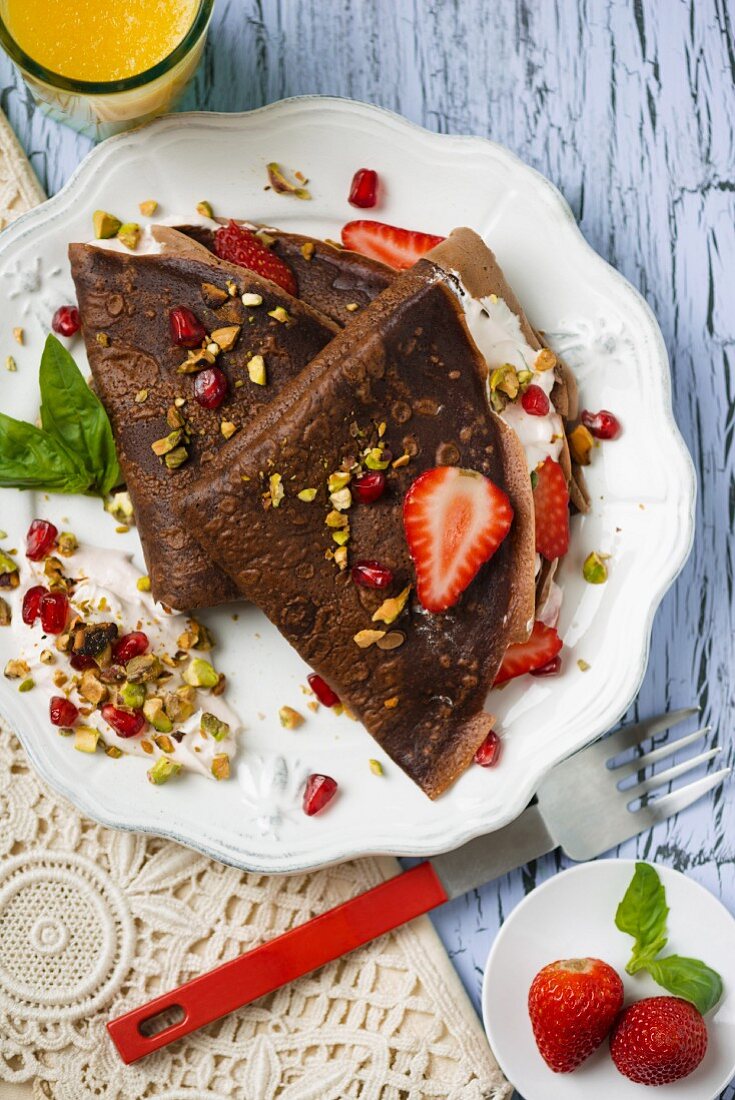 Chocolate pancake with cream, strawberries and pistachios