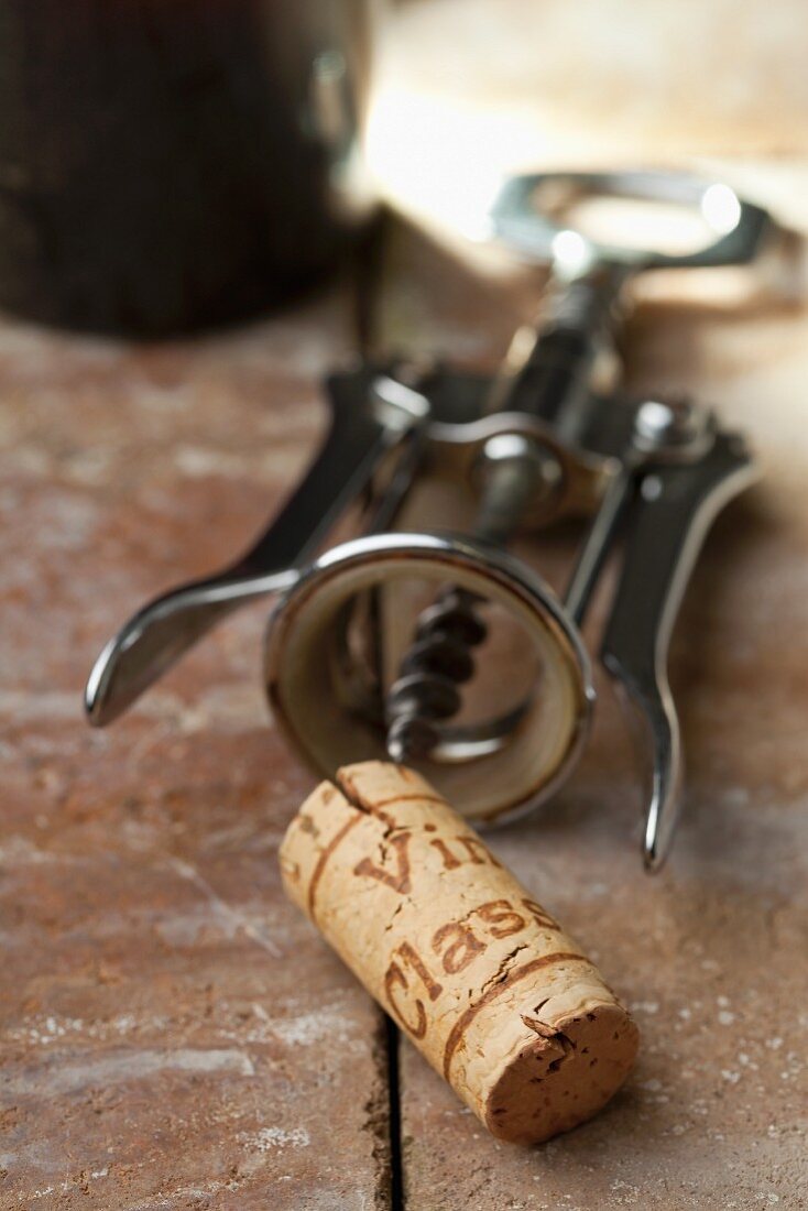 A wine cork with a corkscrew and a bottle of wine