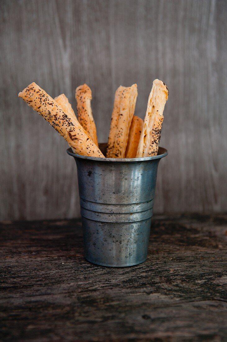 Pastry straws with poppy seeds in a metal container