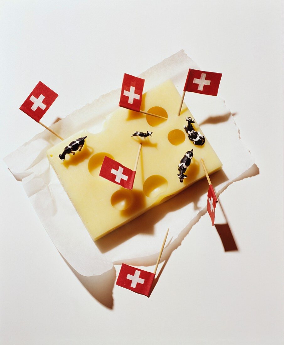 A chunk of cheese decorated with Swiss flags and miniature cow figures