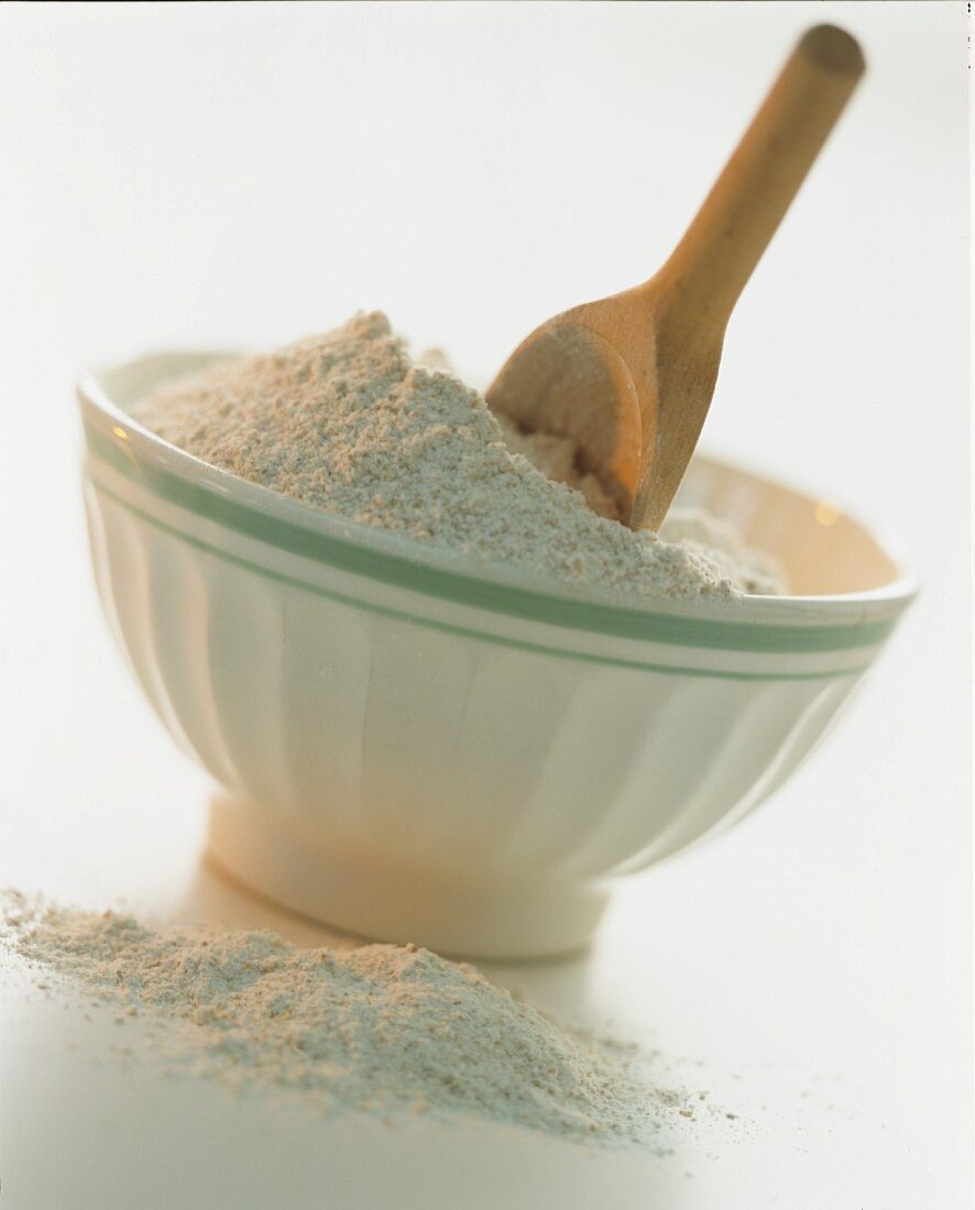 A bowl of flour and a wooden spoon