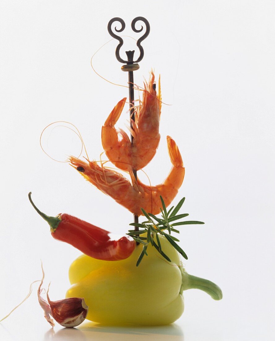 A skewer piercing a pepper, a chilli and whole prawns