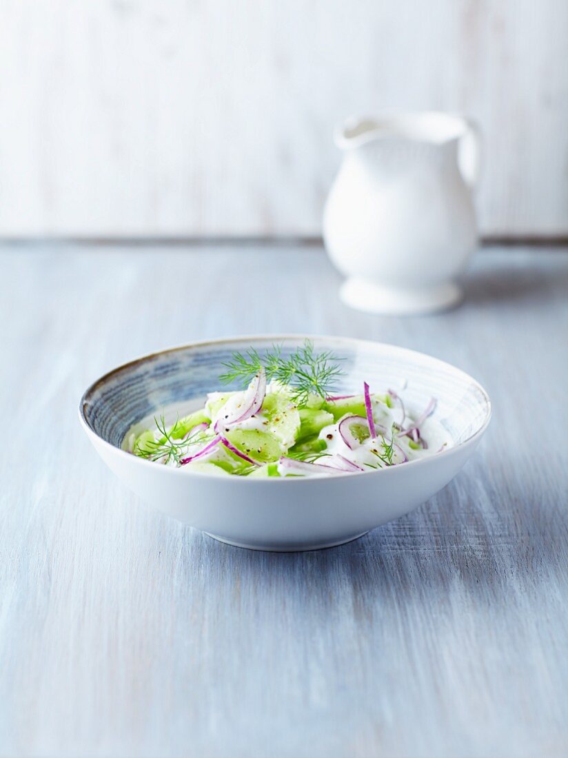 bowl of polish cucumber salad with onion, sour cream and fresh dill