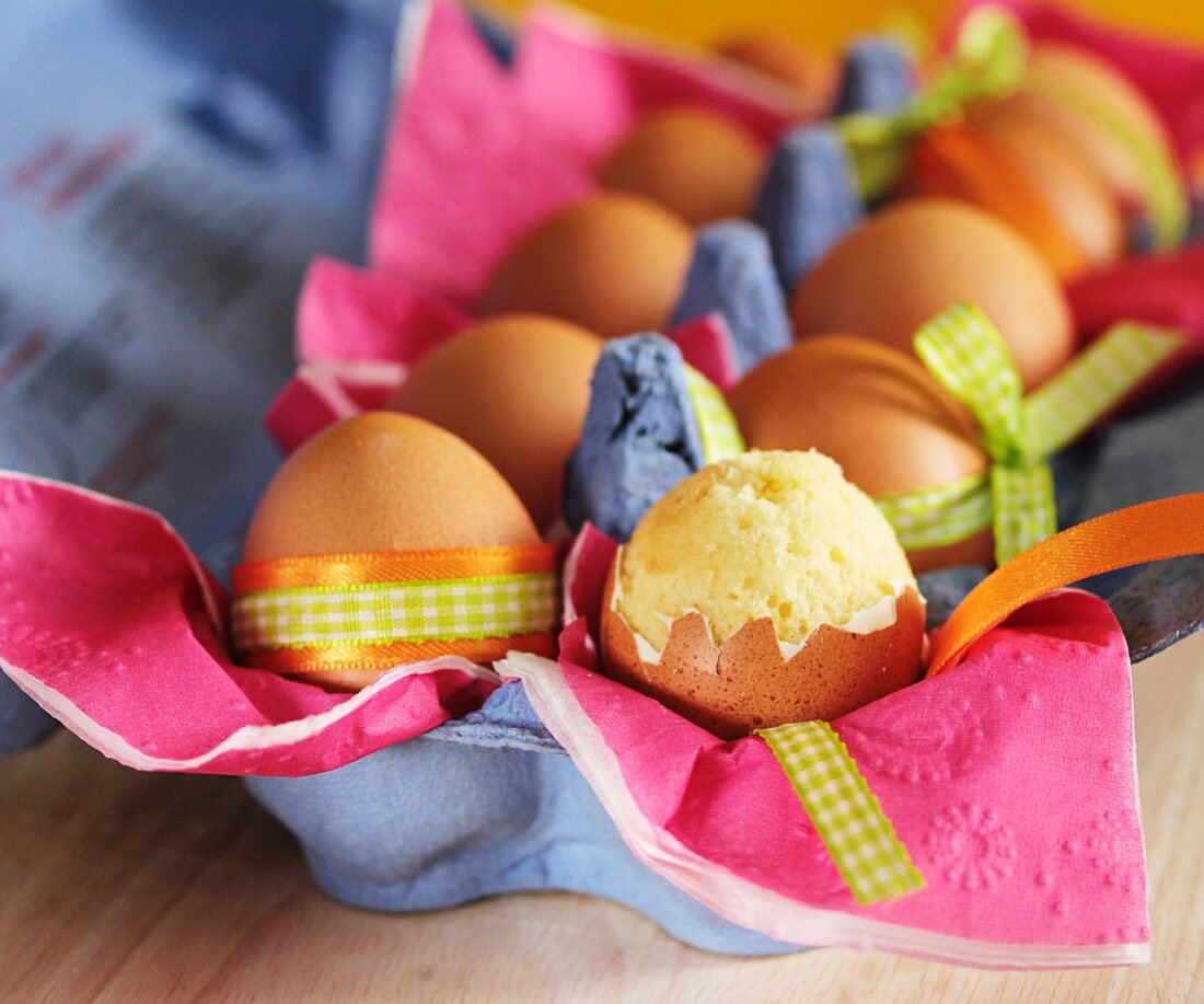 Sponge cake in an eggshell in a full carton of eggs with Easter decorations