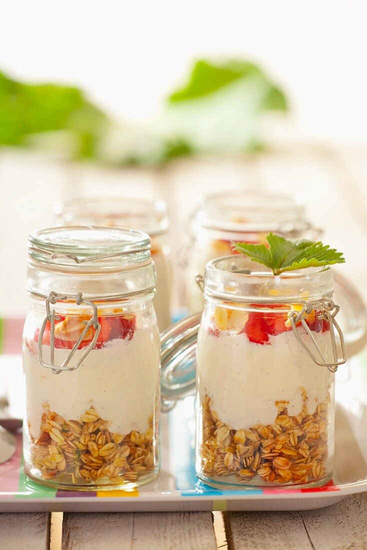 Müsli mit Haferflocken, Joghurt, Erdbeeren und Mandelblättchen in Gläsern