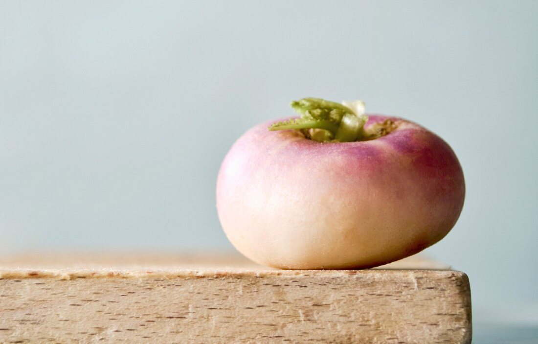 An individual white turnip on a wooden board