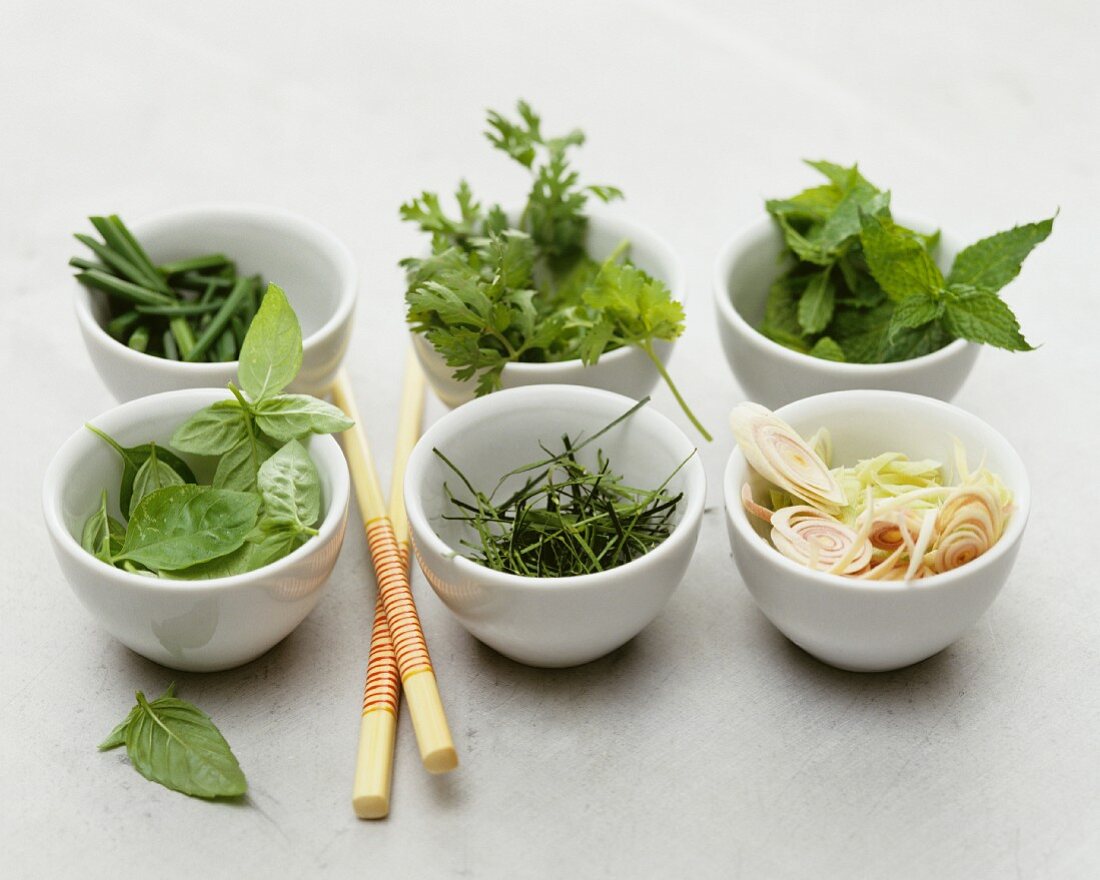 Assorted fresh herbs in small porcelain bowls