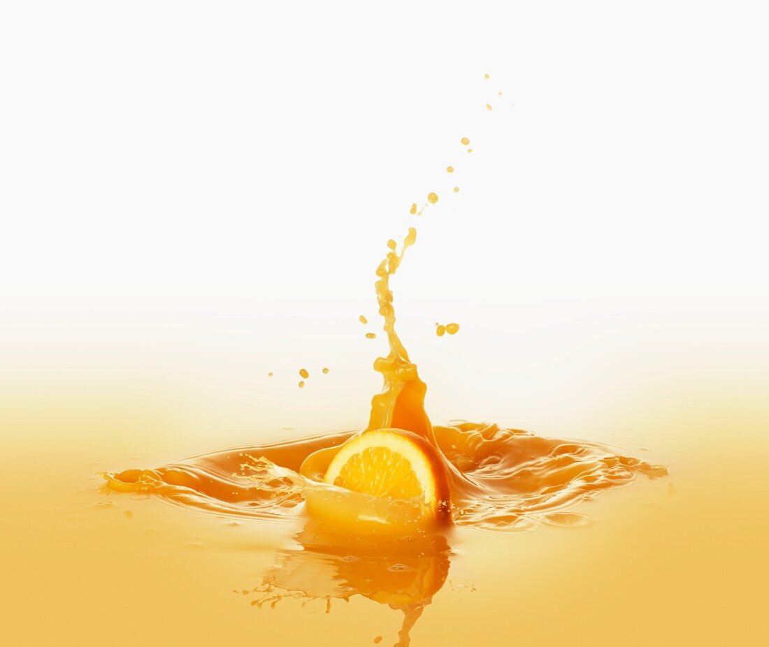 Orange slice falling into orange juice