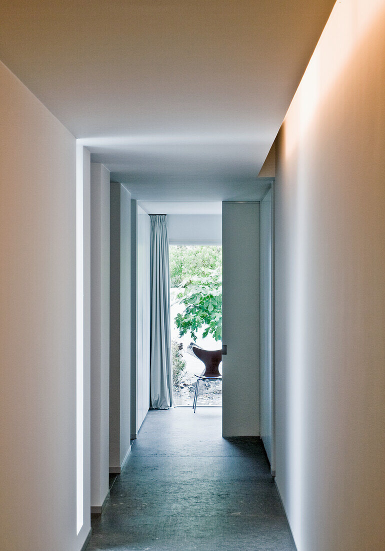 Long, narrow hallway with indirect lighting and view of the greenery