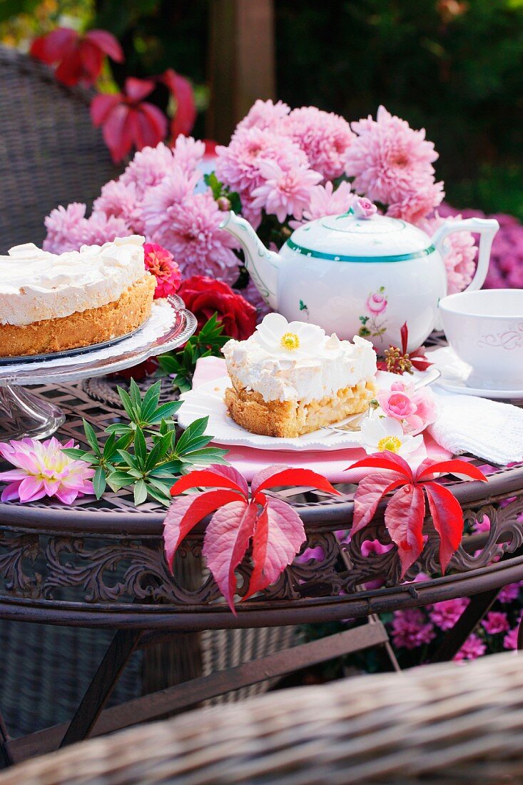 Apple cake, flowers and autumn leaves on a garden table