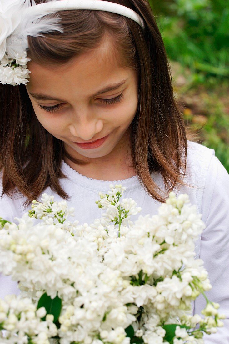 A girl with a bunch of white lilacs in the garden