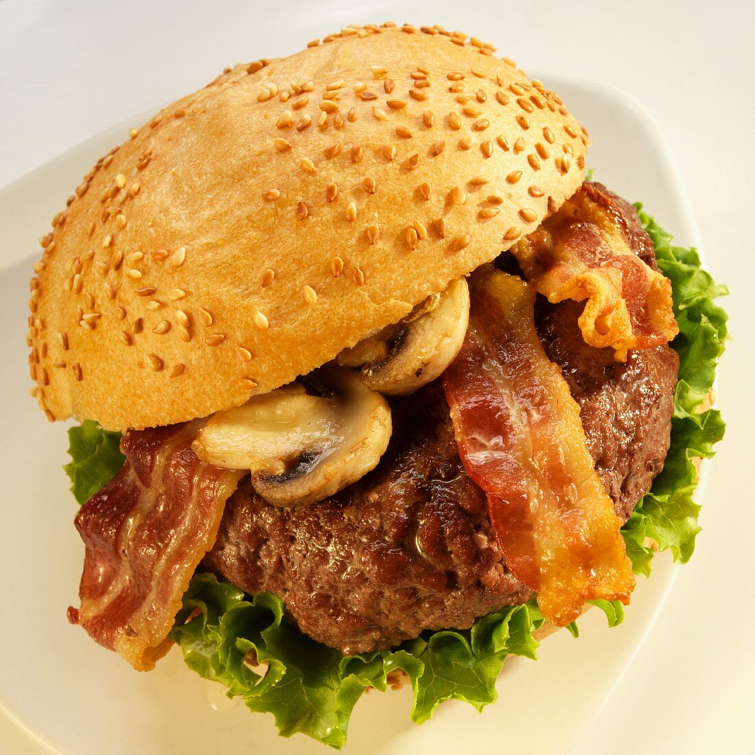 Hamburger with Bacon, Mushrooms and Lettuce on a Sesame Seed Bun