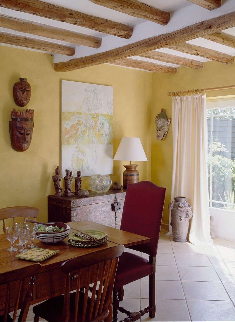 A dining room in an English country house with a wooden table and pieces of art from Nepal and Tibet