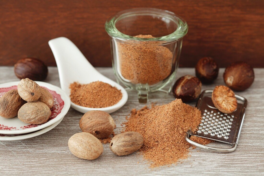 A still life featuring whole, ground and grated nutmeg
