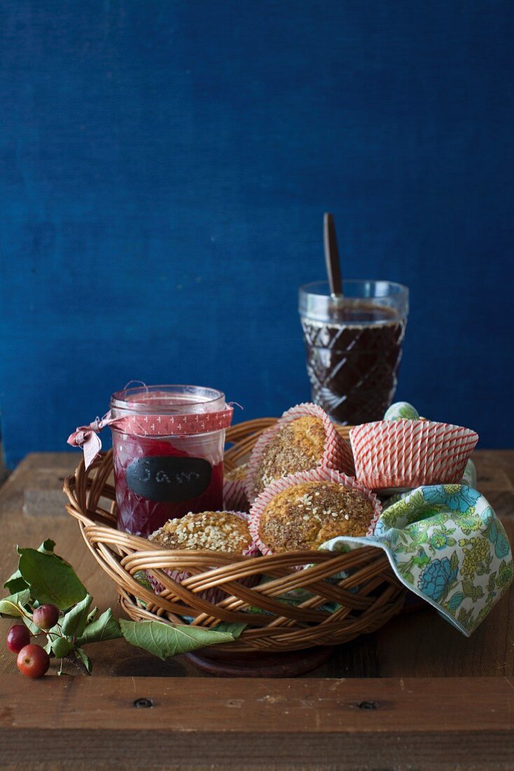 Oat Muffins with a Jar of Jam in a Basket